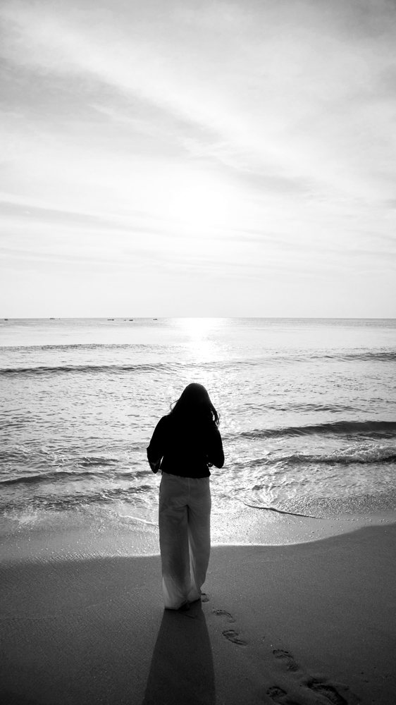 浜辺に立って海を見ている後ろ姿